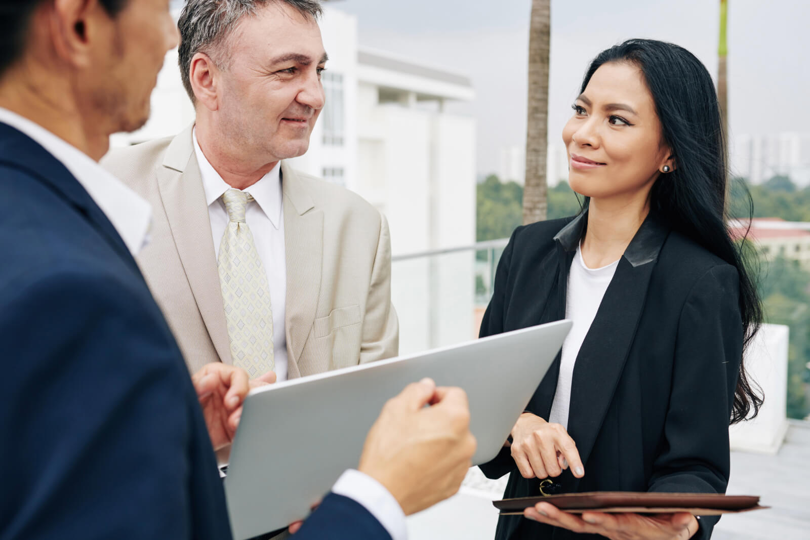Three public adjusters smiling and holding devices