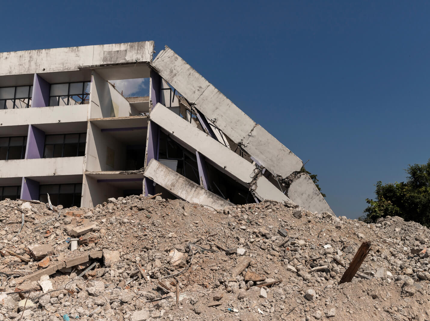 Collapsed commercial building surrounded by a hill of debris