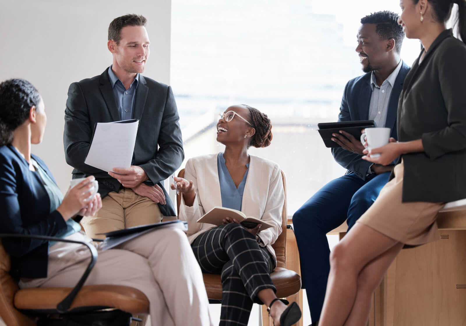 Group of five public adjusters smiling and talking in an office environment