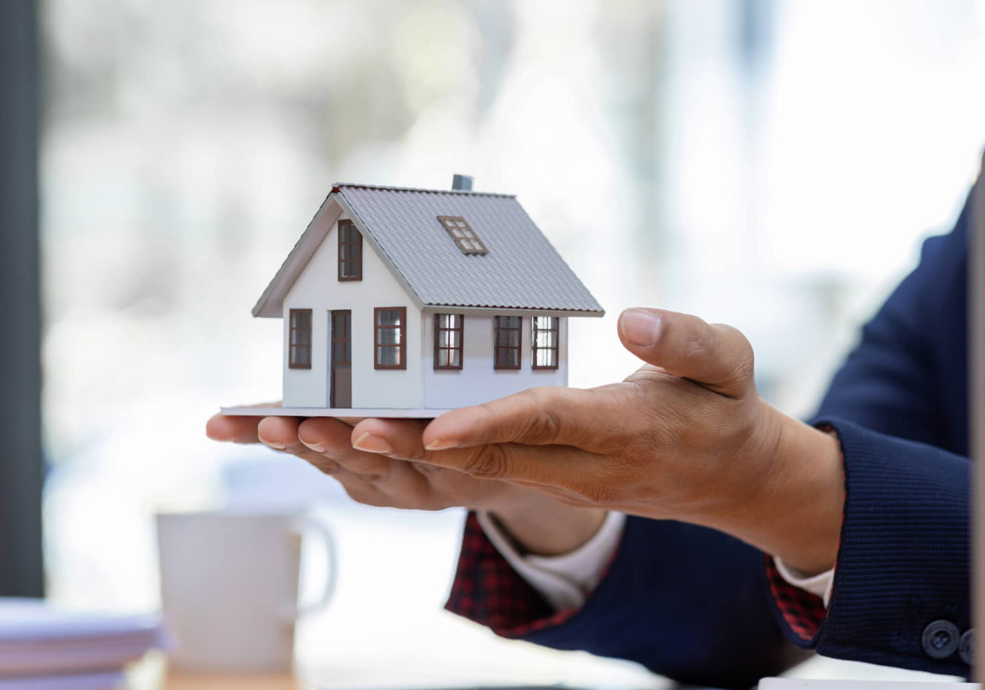 Hand holds a miniature figure of a traditional house