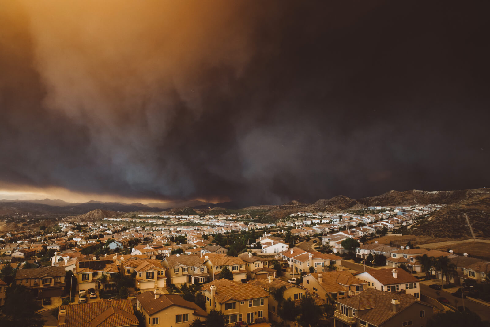 Thick, dark smoke fills the sky of a Californian cityscape